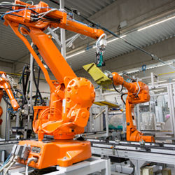 Large orange robotic arms in a factory.