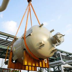 A crane lifting a large industrial tank.