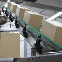 A photograph of cardboard boxes being carried on a conveyor belt.